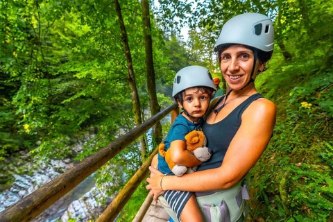 Mother holding her son while wearing helmets and enjoying the stunning view of vintgar gorge near