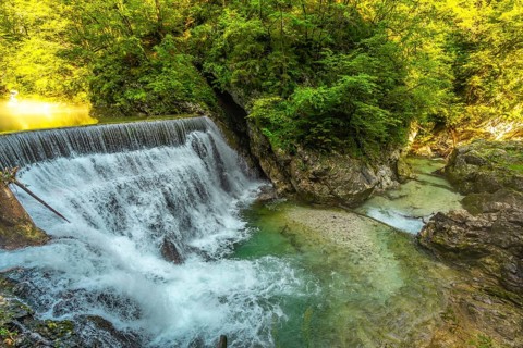Stunning waterfall cascading into the crystal clear turquoise waters of vintgar gorge, a natural