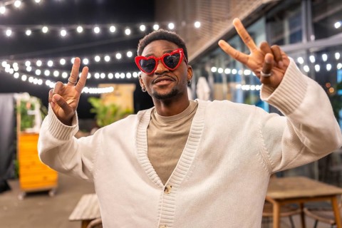 Cool african man gesturing success smiling at camera in a bar terrace at night