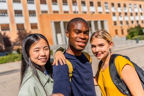 Frontal view of three multi-ethnic university students taking selfie in the campus