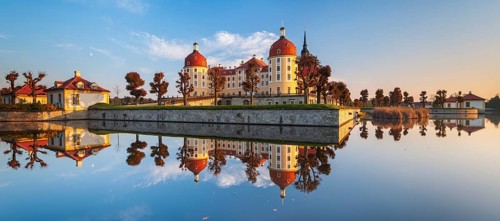 Moritzburg Castle in autumn under a blue sky, reflection in the castle pond, hunting lodge of