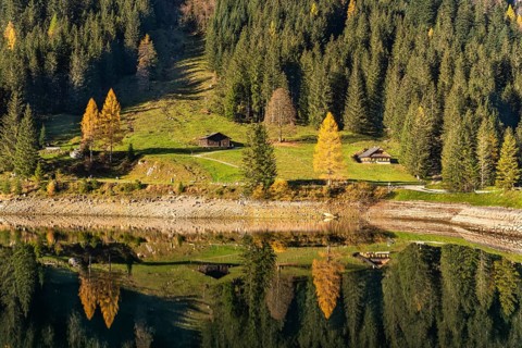 The Vordere Gosausee and the hiking trail around the lake in autumn. Two typical houses. Yellow