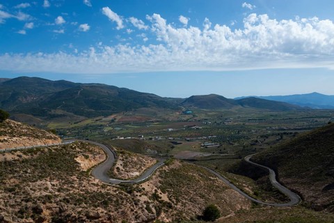 Mountain landscape with serpentine road in green valley under blue sky with clouds, road to Mirador
