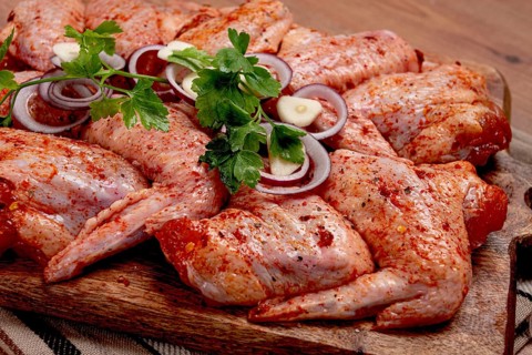 Chicken wings, marinated and laid out on a wooden platter, ready for cooking, grilling or baking,