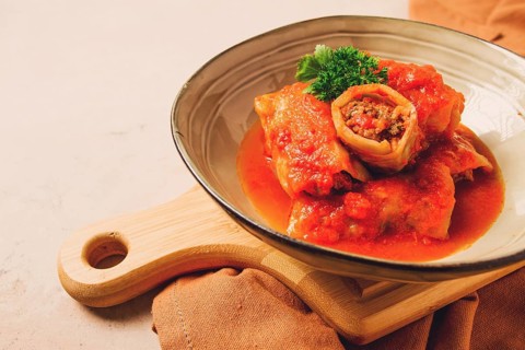 Stuffed cabbage rolls, with minced meat, in tomato sauce, on a beige background, food and drink,