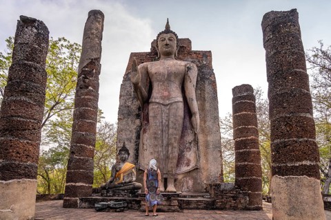 Tourist in front of the giant standing Buddha in the temple Wat Saphan Hin, UNESCO World Heritage
