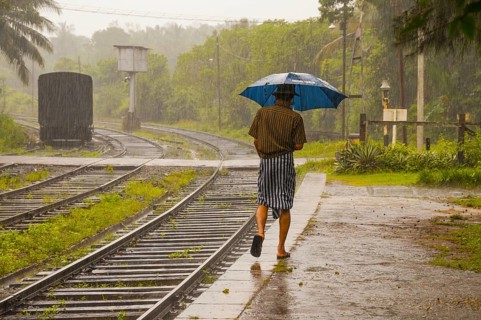 Sinhalese with umbrella in heavy rain, monsoon, railway station in Kalawewa, Sri Lanka, Ceylon,