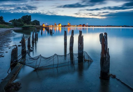 View at dusk over the Strelasund to the illuminated town of Stralsund with its churches and the