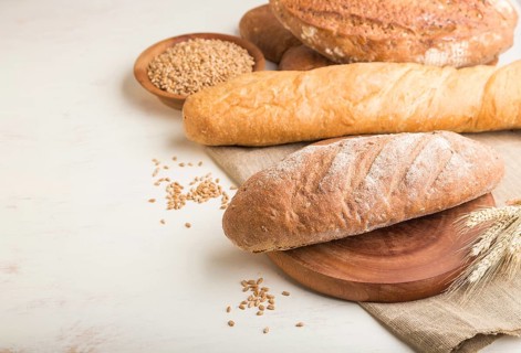 Different kinds of fresh baked bread on a white wooden background. side view, close up, copy space