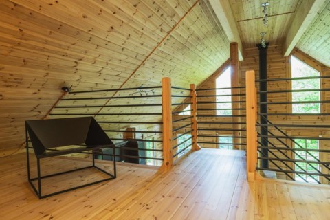 Black metal sitting chair and tubular railings with wooden posts in home office set-up on mezzanine