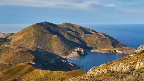 Sunny coastal road winding along a mountainous landscape overlooking the sea, southern tip, Mani
