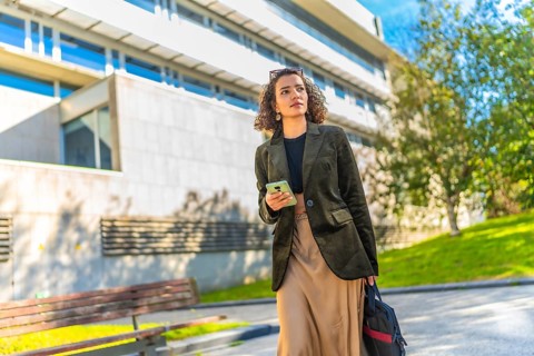 Low angle view photo of an Arab young freelancer using mobile walking along the city