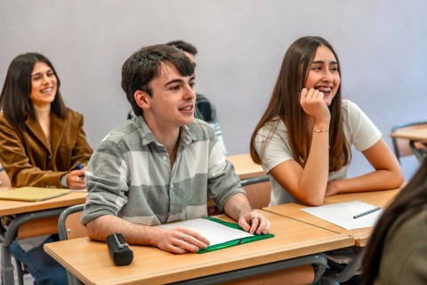 Group of happy and smiling students listening to their teacher in a classroom at their university
