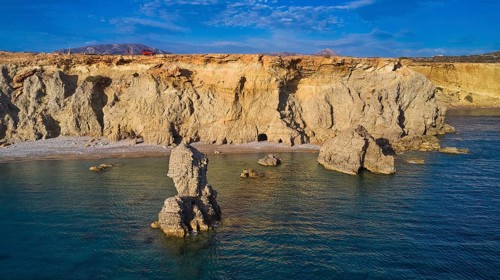 Impressive coastal landscape with imposing rock formations under a clear sky, drone shot, evening