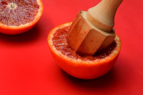 Halved blood orange with citrus squeezer, orange