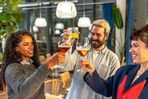 Multi-ethnic friends raising glasses and toasting celebrating success at night party in a bar