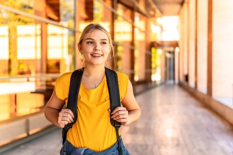 Portrait of a blonde happy female student standing at the university