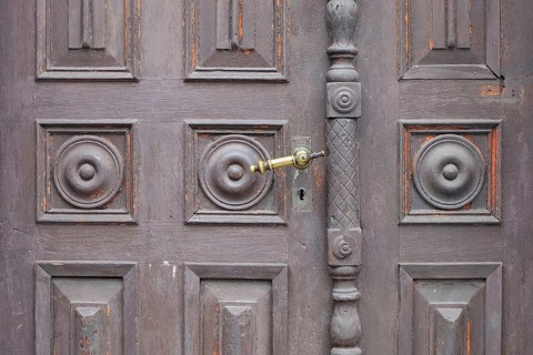 Old antique wooden door with decorative round patterns and a metal door handle, St. Martin,