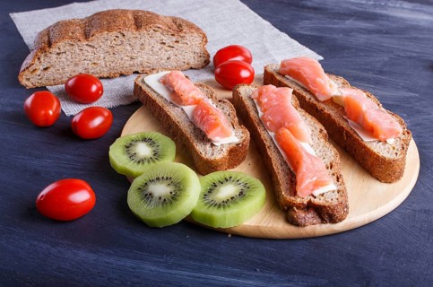 Smoked salmon sandwiches with butter on dark wooden background. cherry tomatoes. close up