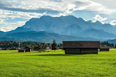 Green meadow with hay huts, behind Kranzberg, mountains Obere Wettersteinspitze, Rotplattenspitze,