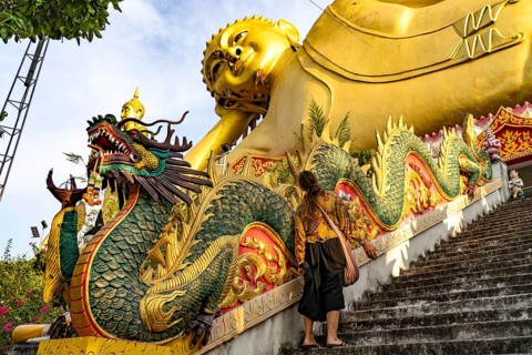 Tourist in front of the huge reclining Buddha statue of the Buddhist temple Wat Mokkanlan in Chom