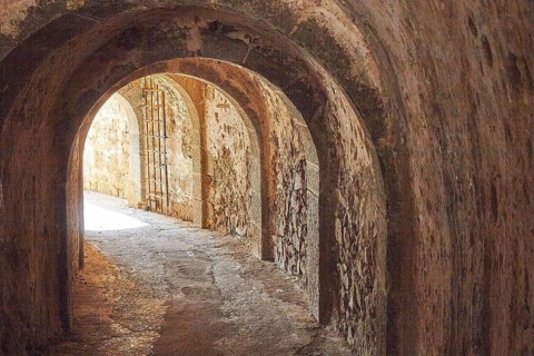 An old, dark tunnel with stone walls and a glow of light at the end, Venetian Sea Fortress, Leper