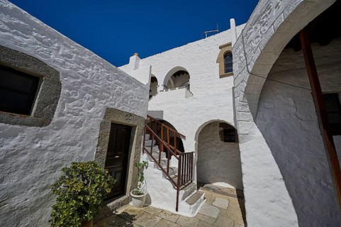 Courtyard of a historic building with white walls and a wooden staircase, Inside the monastery,