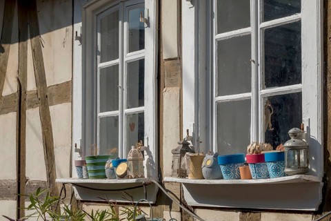 Two mullioned windows in a half-timbered house, window sills decorated with flower pots and