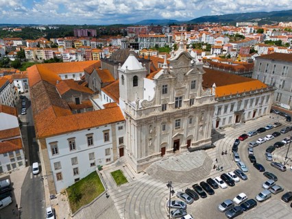 Historic baroque church in the city with a square in front of it and parked cars, aerial view,