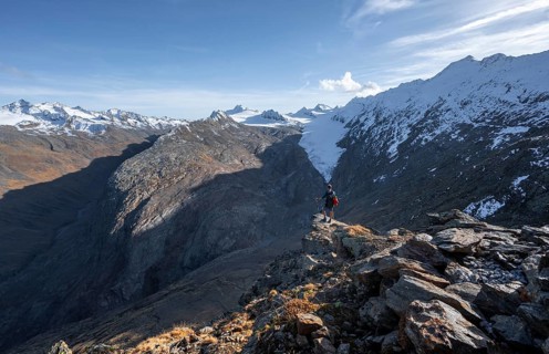 Mountaineer standing on a rock, surrounded by an impressive mountain landscape with snow-covered