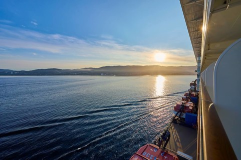 View from a cruise ship, Mein Schiff 6, of the calm sea at sunrise with soft clouds in the sky,