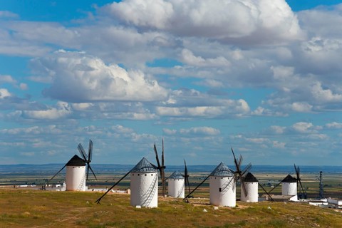 Panoramic view of several white windmills in a vast landscape under a slightly cloudy sky, Campo de