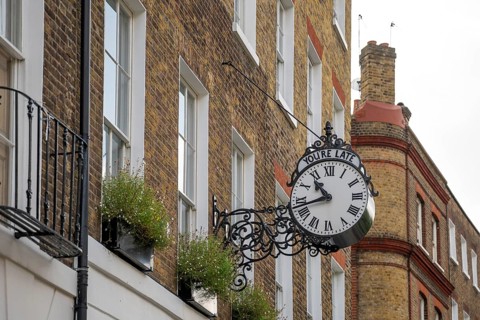 Classic clock with original lettering You're late on a building facade, Doughty Street, Holborn,