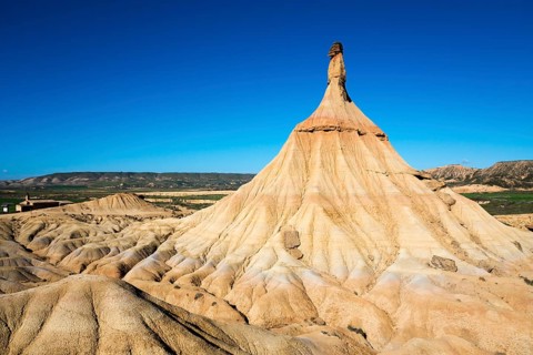 A striking rock formation in a desert landscape under a clear blue sky, Castildetierra, Bardenas