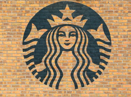 Starbucks coffee logo symbol stencilled onto wall of yellow bricks, Liverpool, Merseyside, England,