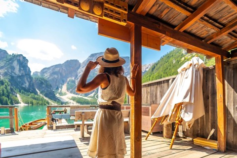 Woman wearing straw hat enjoying stunning panorama of lake braies, also known as pragser wildsee,