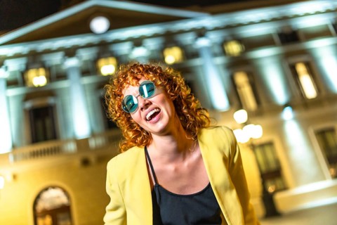 Sensual modern woman in sunglasses dancing along the city at night