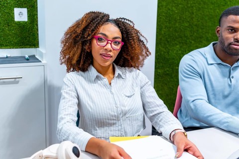 Two young professionals are working together in a modern coworking space, focused on a shared