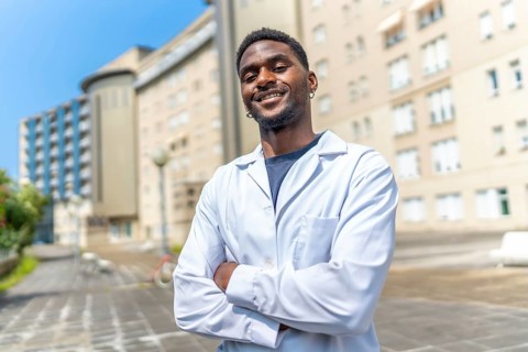 Portrait of an african doctor smiling at camera with arms crossed outside the hospital