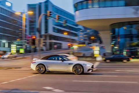 Car at night in front of urban surroundings with modern architecture, pull-along. Mercedes-Benz SL
