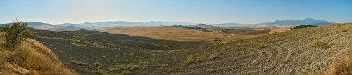 Typical Tuscan landscape in Val d'Orcia with hills, trees, fields, farmhouses and cypresses in