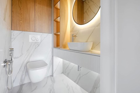 This contemporary bathroom showcases minimalistic design with marble walls and a circular mirror,