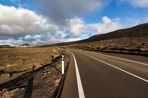 Empty country road through wine-growing area, typical landscape with volcanic mountains, La Geria,