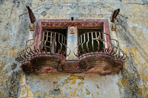An abandoned balcony with rusty railings and damaged façade on an old building, Italian Governor's