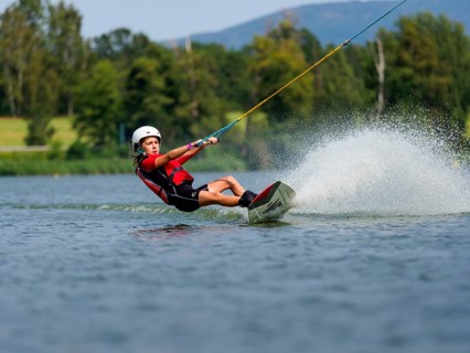 Boy or girl, summer holiday with wakeboard, water splashes, red life jacket, water skiing and