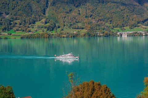 A boat sails across a calm lake in front of a picturesque mountain landscape, Lake Brienz,