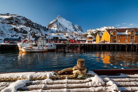 Fishing village with yellow and red houses in front of snow-covered mountains, Nusfjord,