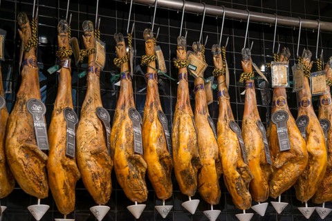 Reihe von traditionell aufgehängten Schinken in einem Delikatessengeschäft, Mercado da Ribeira,