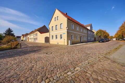 Residential building, cobblestone pavement, blue sky with cirrostratus clouds, intersection of