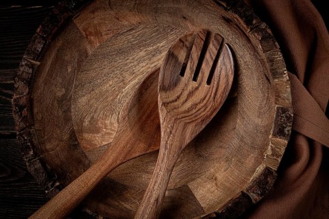Wooden plate, handmade, with salad spoons, top view, on a wooden table, no people